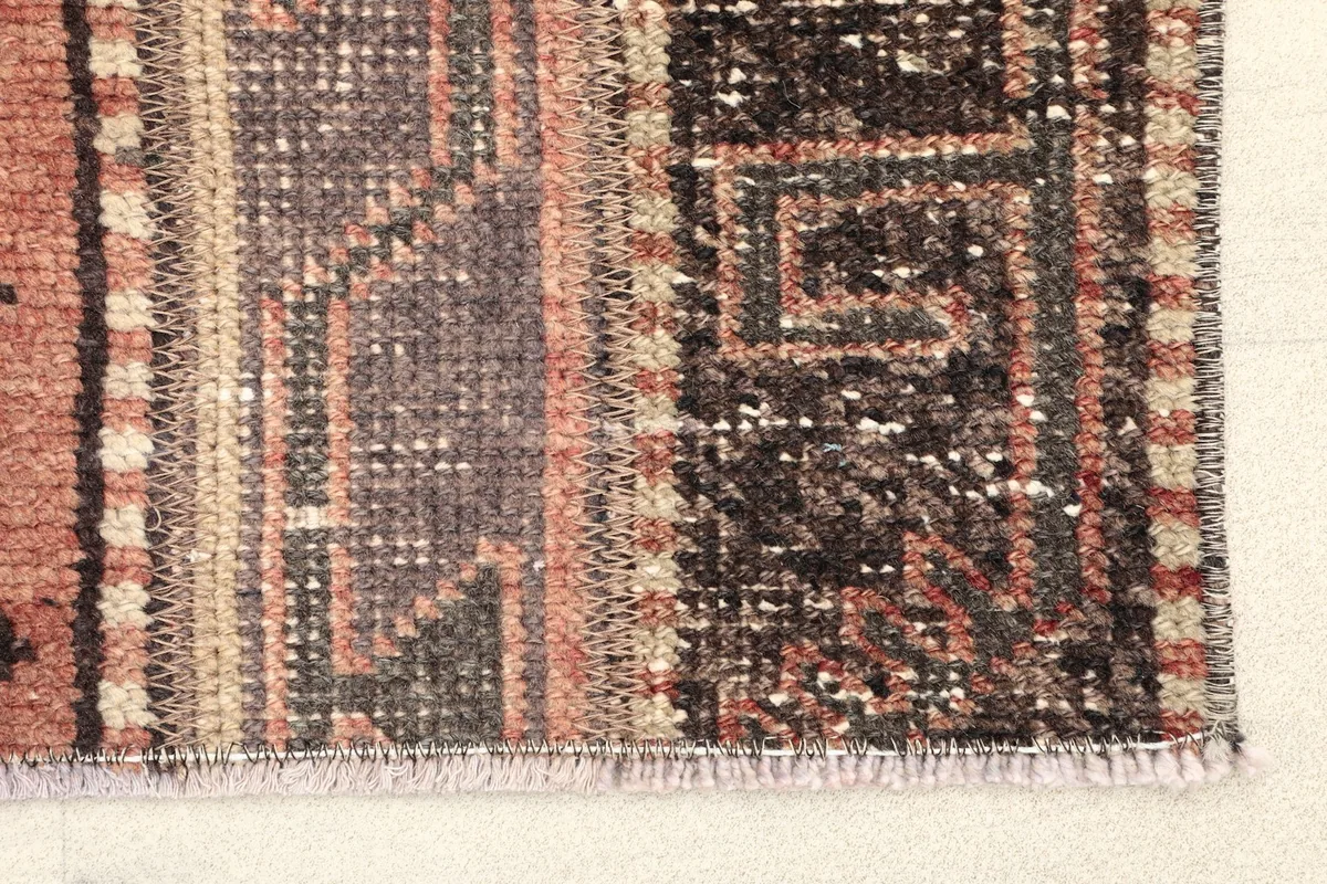 Close-up detail of the rug's edge, showing the intricate hand-knotting and varied brown and rust tones.