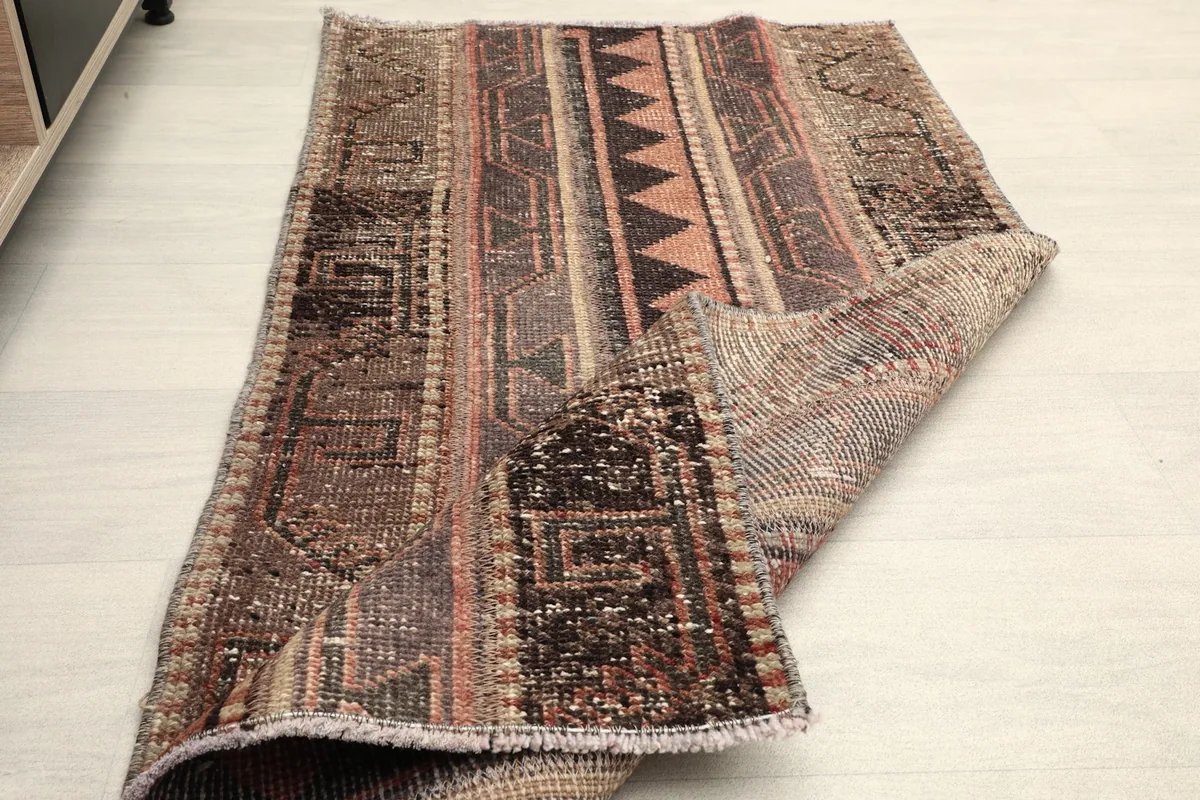 Rug partially folded, illustrating its flexibility and the overall appearance of the vintage piece.