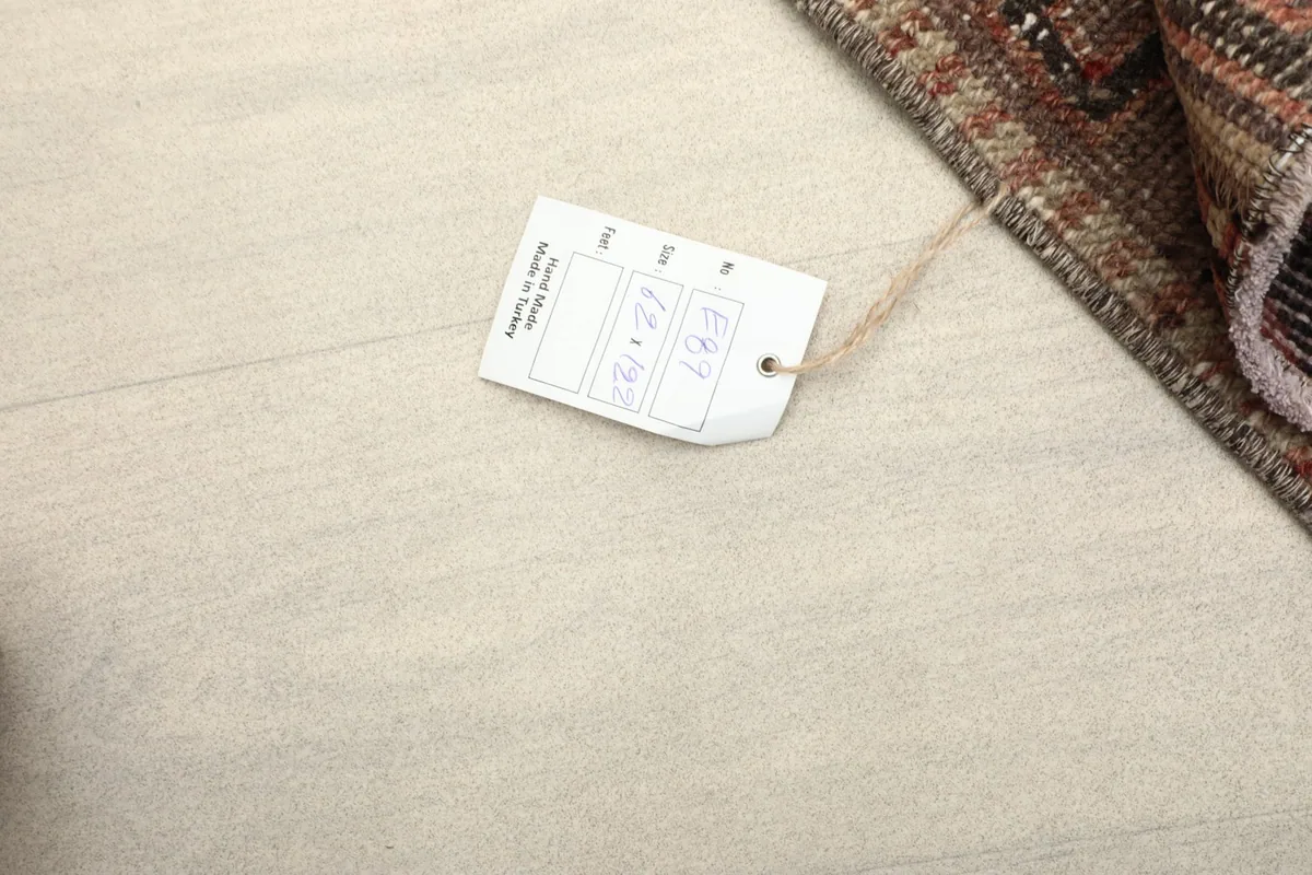 Close-up of the product tag with size information, resting on the rug's foundation.