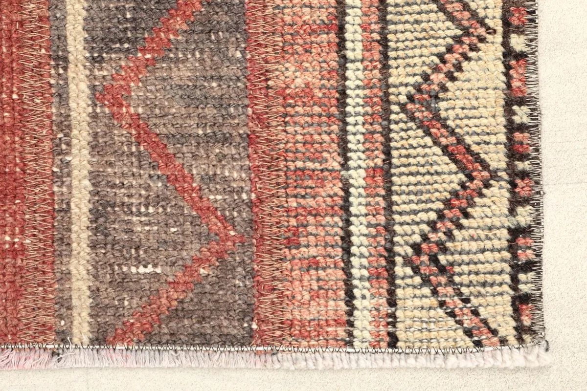 Close-up detail of the rug's end, highlighting the red and beige zigzag border and texture.