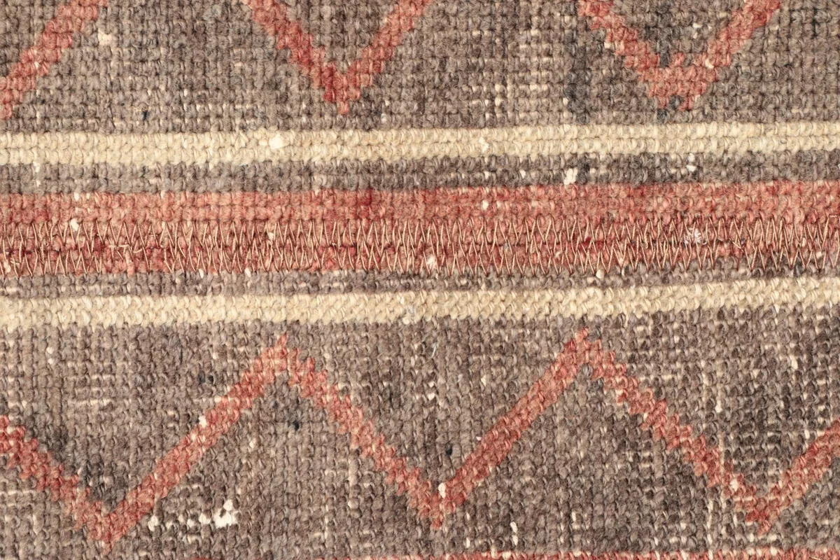Detailed view of the rug's central design, featuring a mix of stripes and geometric motifs.
