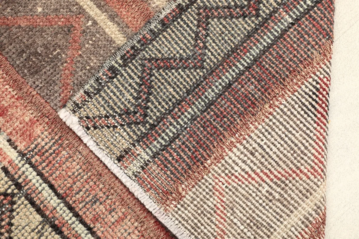 View of the rug's underside and folded edge, revealing the hand-knotted cotton foundation.