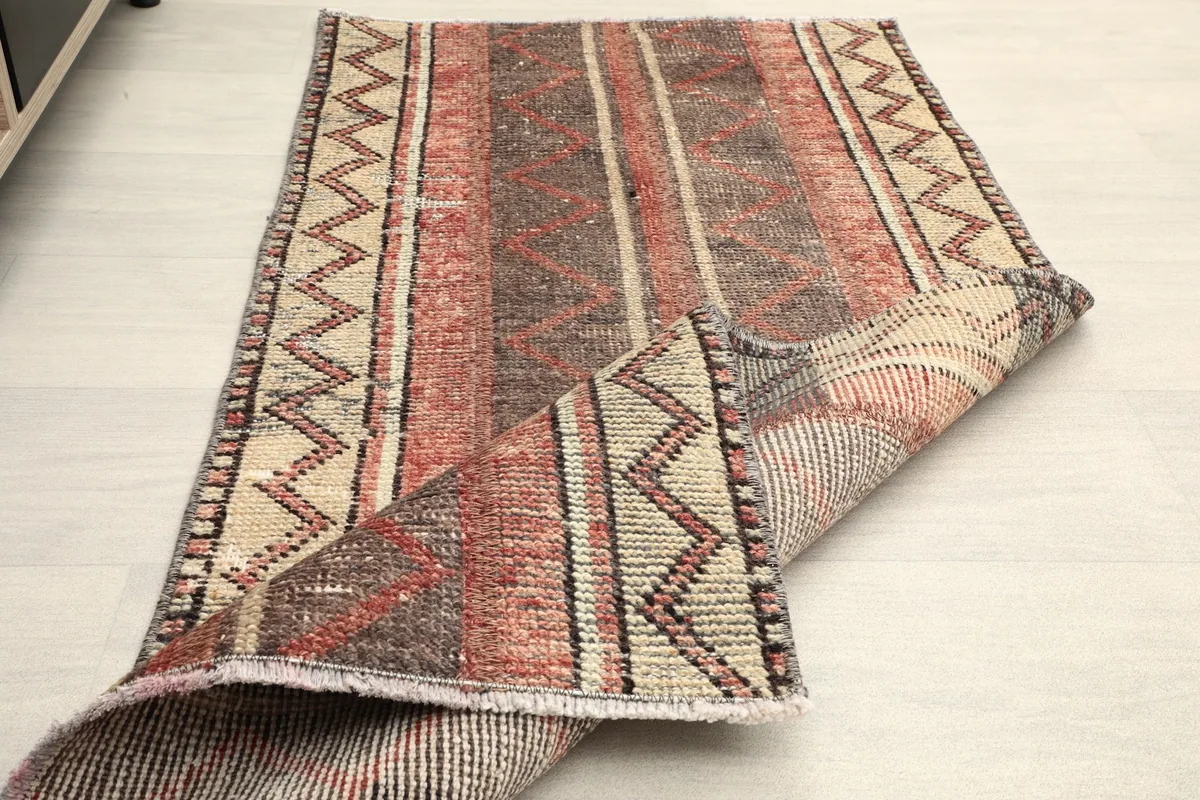 Rug partially folded, displaying the thickness and flexibility of the vintage wool pile.