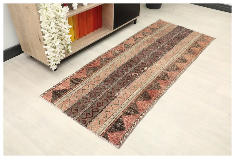 Full top view of the rust geometric striped runner rug on a white floor in a room setting.