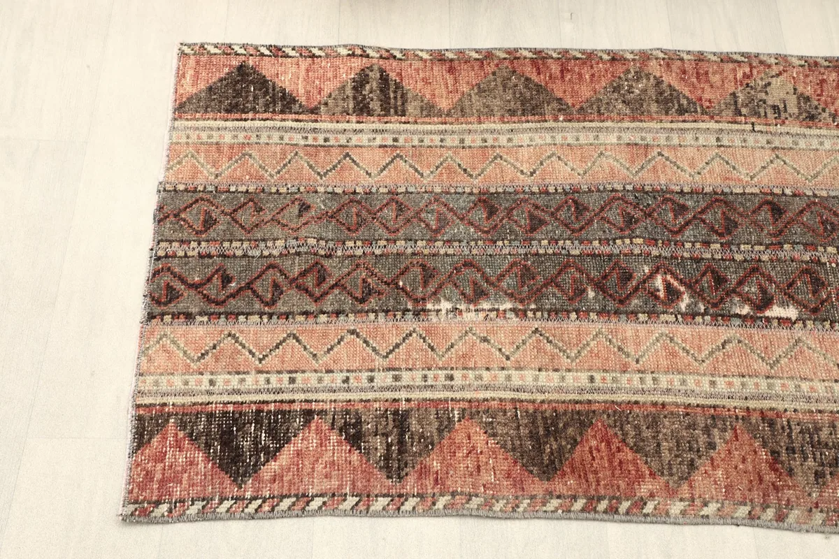 Partial view of the rug's surface, focusing on the blend of rust, brown, and beige geometric designs.