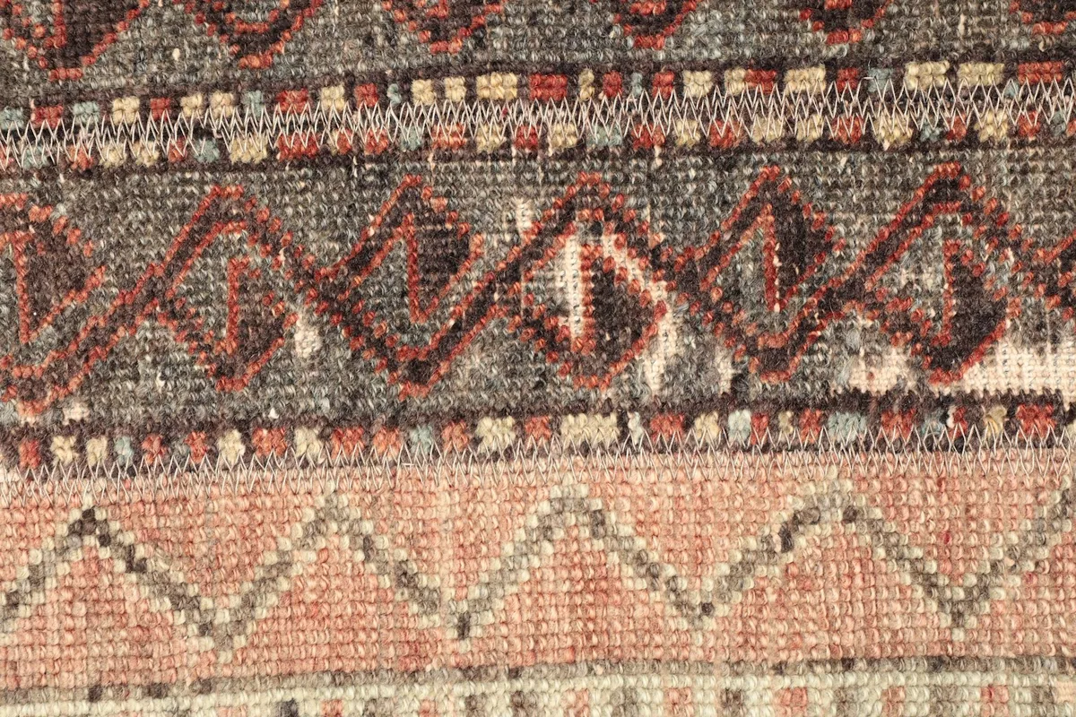 Detailed view of the low wool pile and intricate geometric patterns, revealing the vintage character.