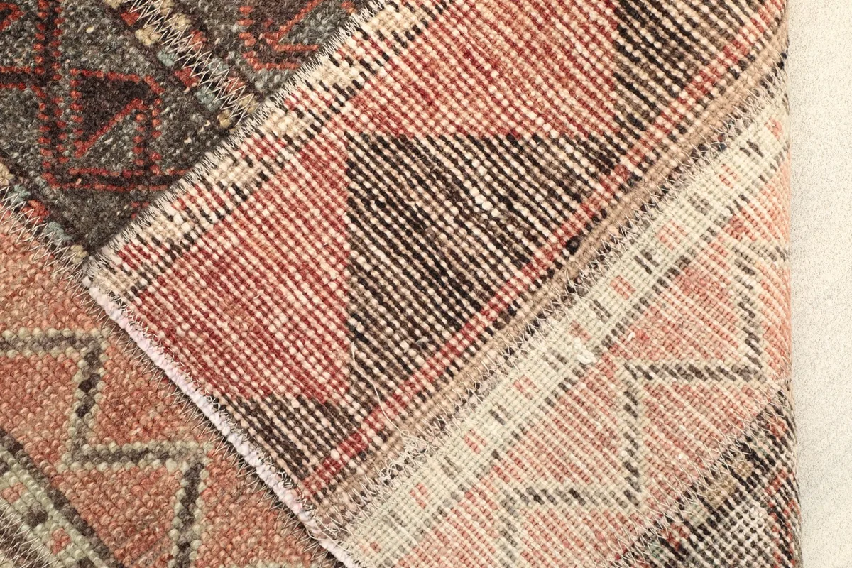 View of the rug's reverse side and folded corner, showing the hand-knotted construction and cotton foundation.