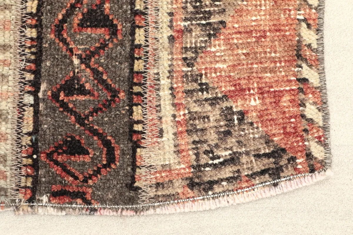 Close-up of one end of the rug, showing the wool pile, cotton foundation, and hand-knotted texture.