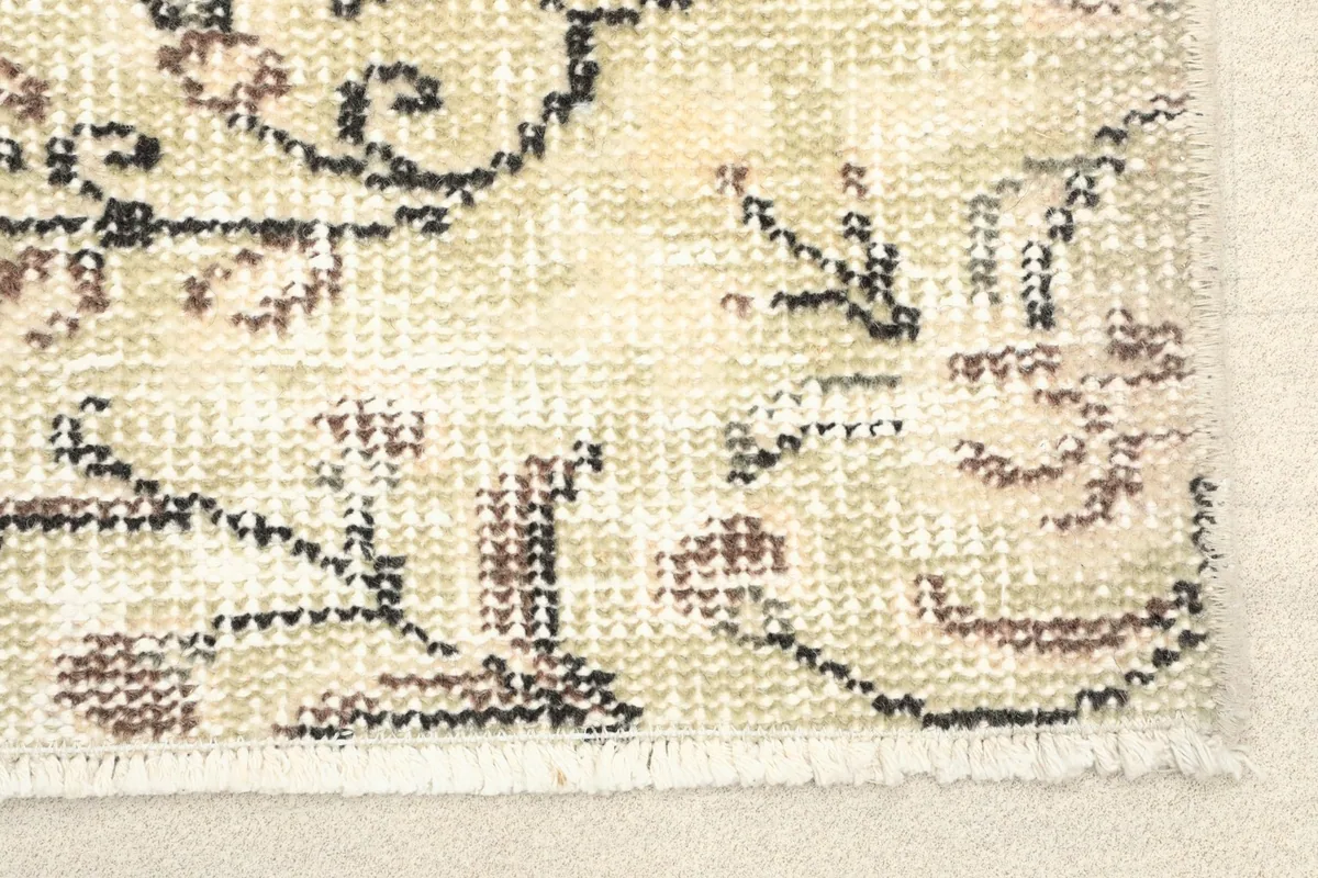 Close-up detail of the rug's border and fringe, showing the hand-knotted wool pile and cotton foundation