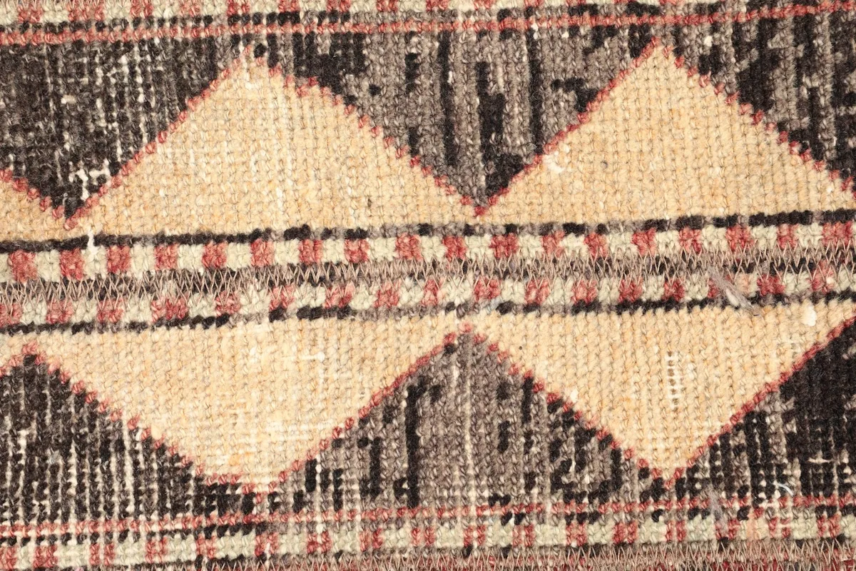 Tight detail shot of the central geometric diamond and zigzag patterns in beige, black, and gray
