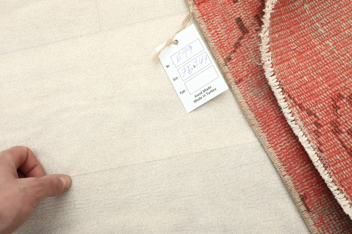 View of the rug's reverse side and a product tag, illustrating the cotton foundation.
