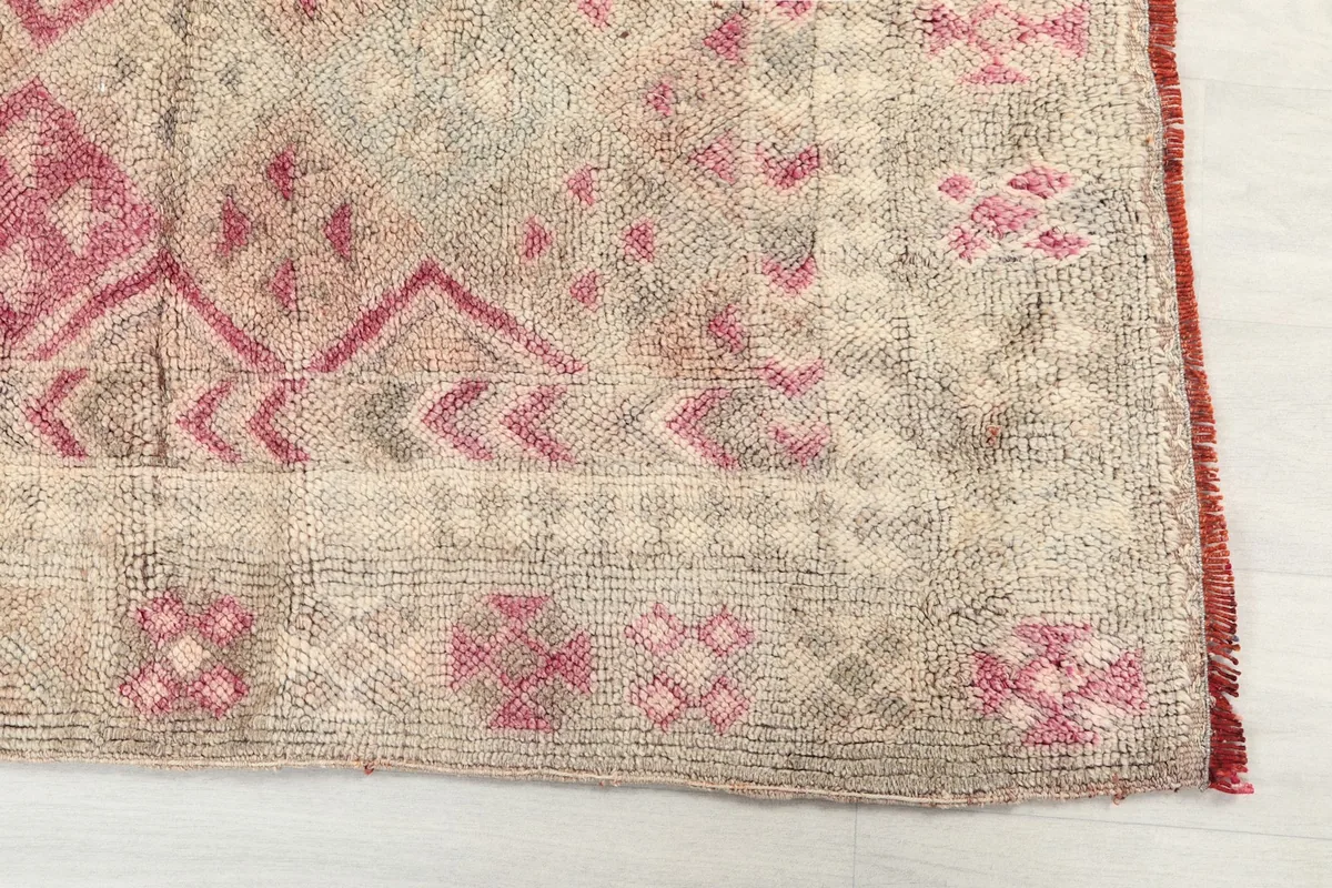Detail of the rug's border and main field pattern, highlighting the pink and gray tones