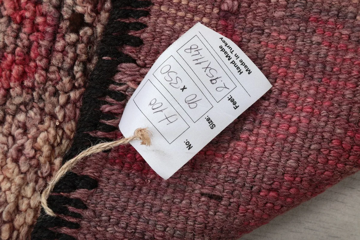 Product tag attached to the rug, displaying its dimensions and origin