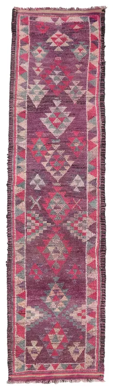 Full overhead view of a vintage purple geometric tribal runner rug on a white background.