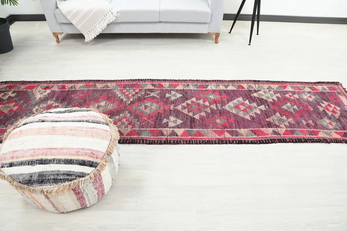 Long shot of the purple runner rug in a room, showcasing its narrow shape and tribal design.