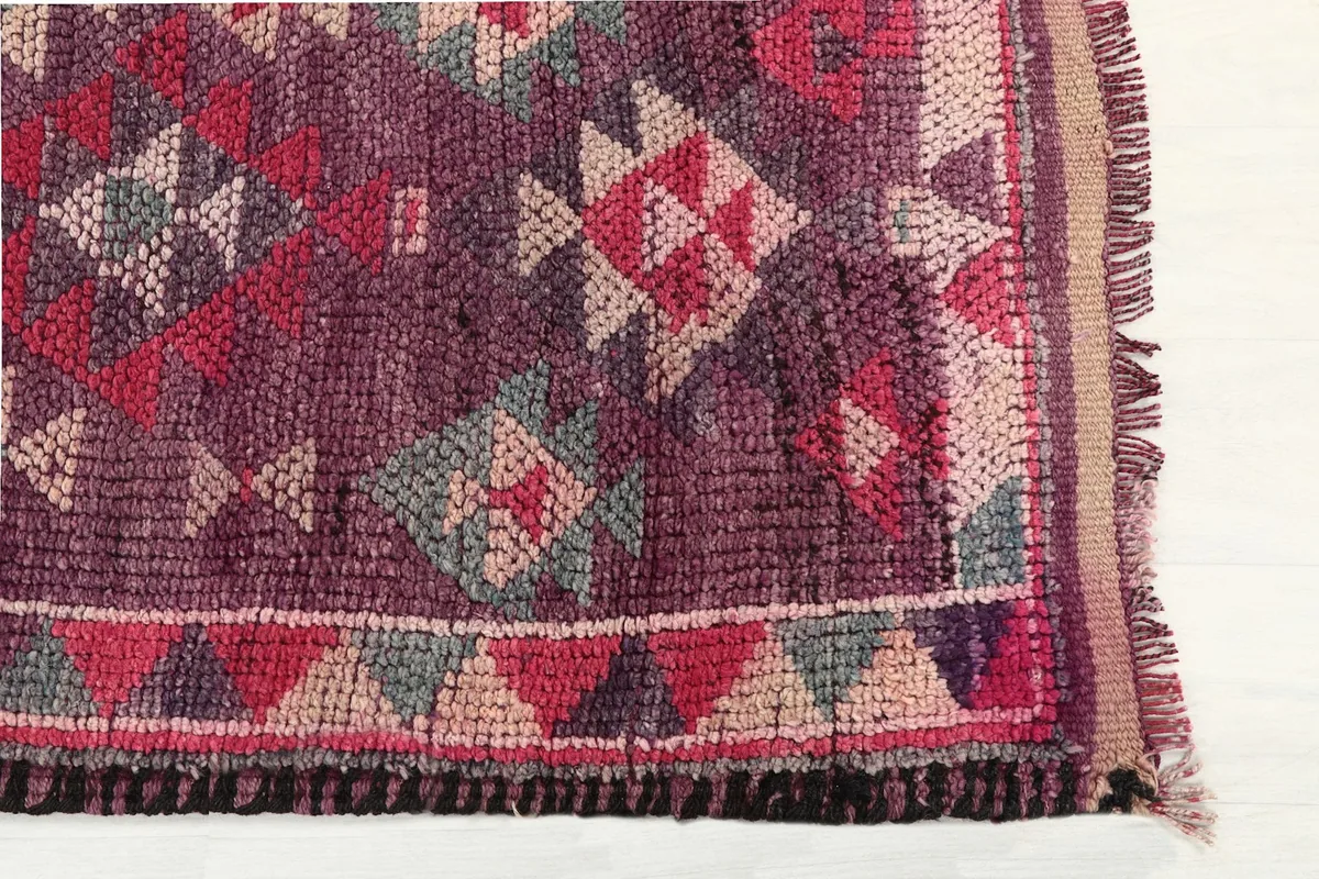 Detailed view of the purple rug's geometric motifs and border design, highlighting texture.