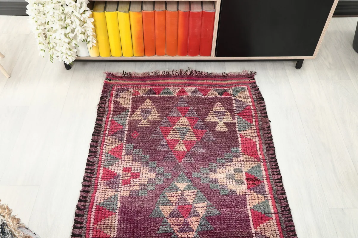 Overhead view of one end of the purple runner rug, showing the patterns and fringe.