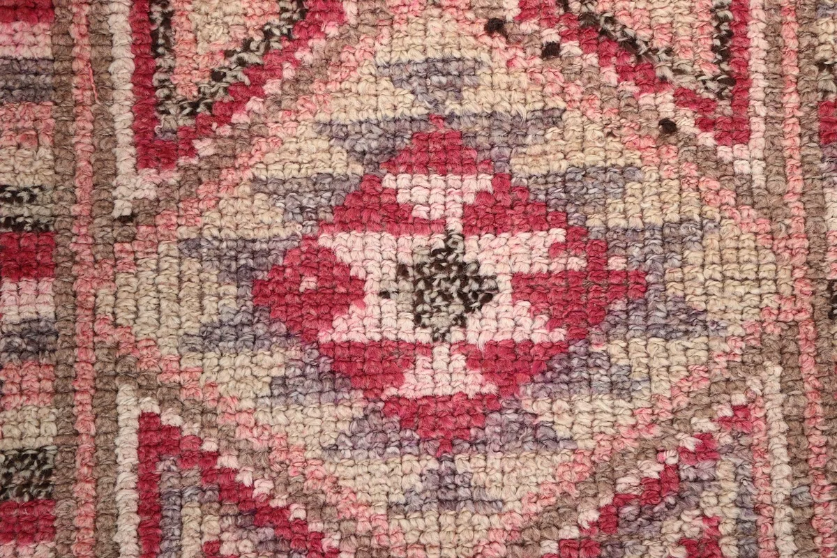 Extreme close-up of a prominent diamond motif in the rug, highlighting individual knots and colors
