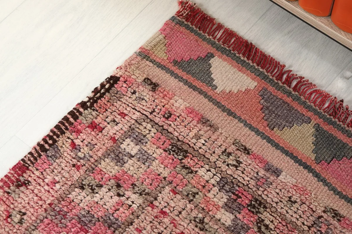 Close-up of the rug's border design and fringe, revealing the subtle color variations