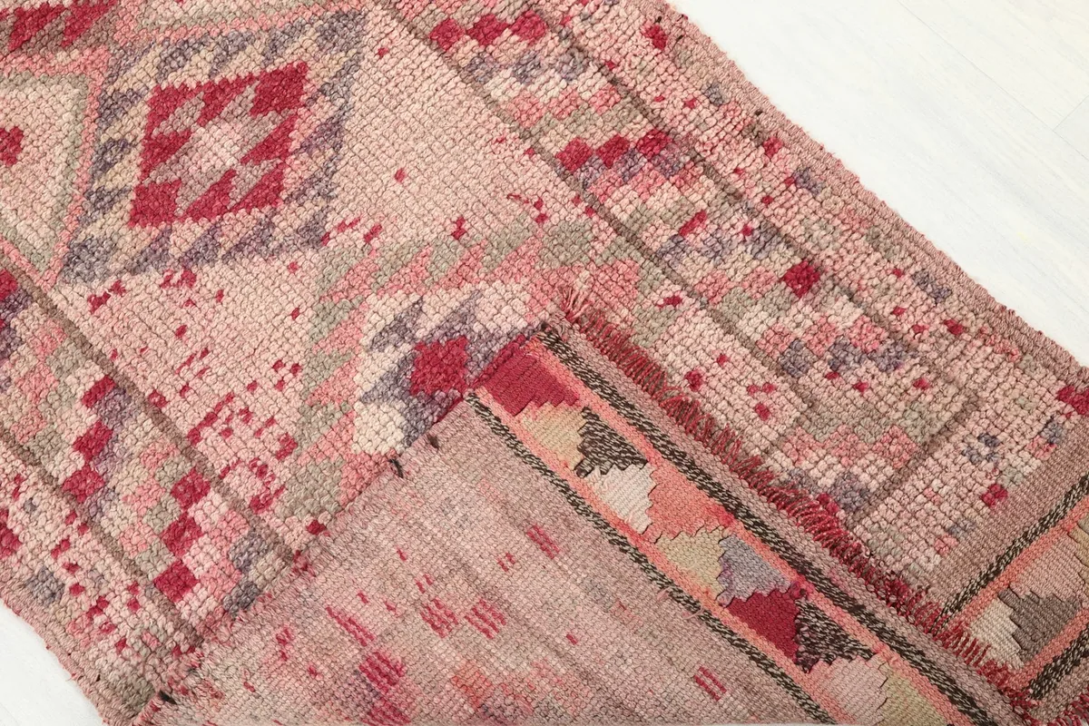 Folded corner of the rug revealing the cotton foundation and reverse side of the hand-knotted wool pile