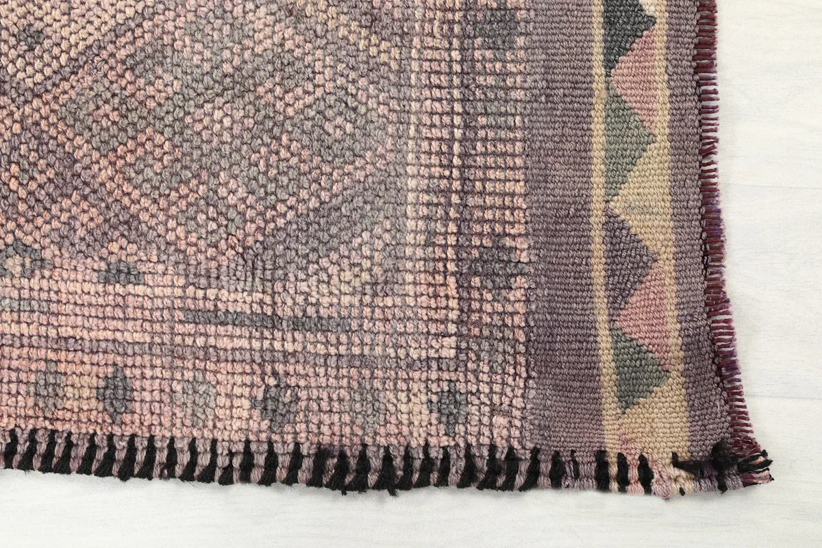 Detailed view of the rug's end, showing the geometric border and fringe.