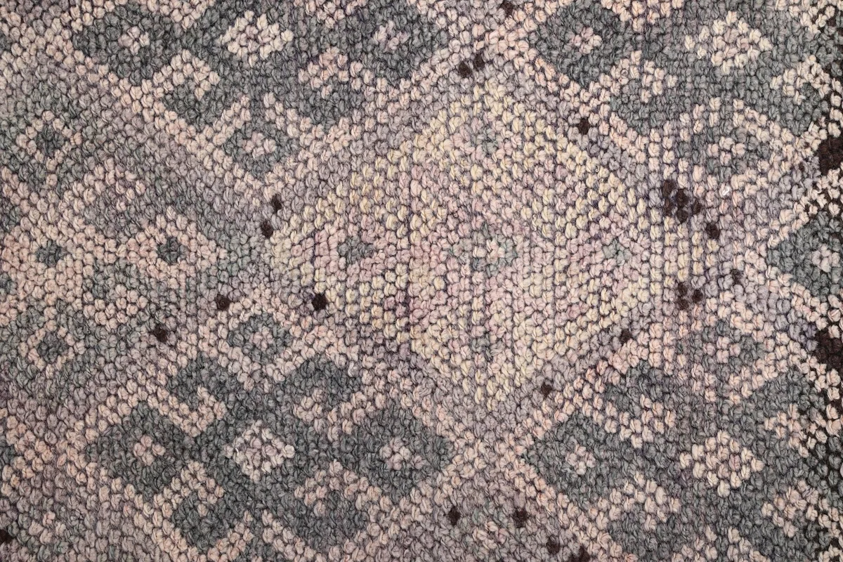 Close-up of the hand-knotted wool pile, revealing the varied rose, gray, and charcoal tones.