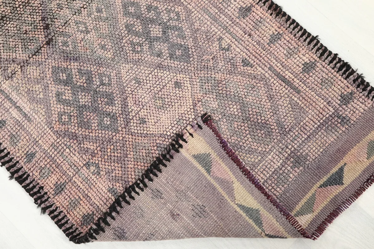 View of the rug flipped to show the cotton foundation and the reverse side of the hand-knotted construction.