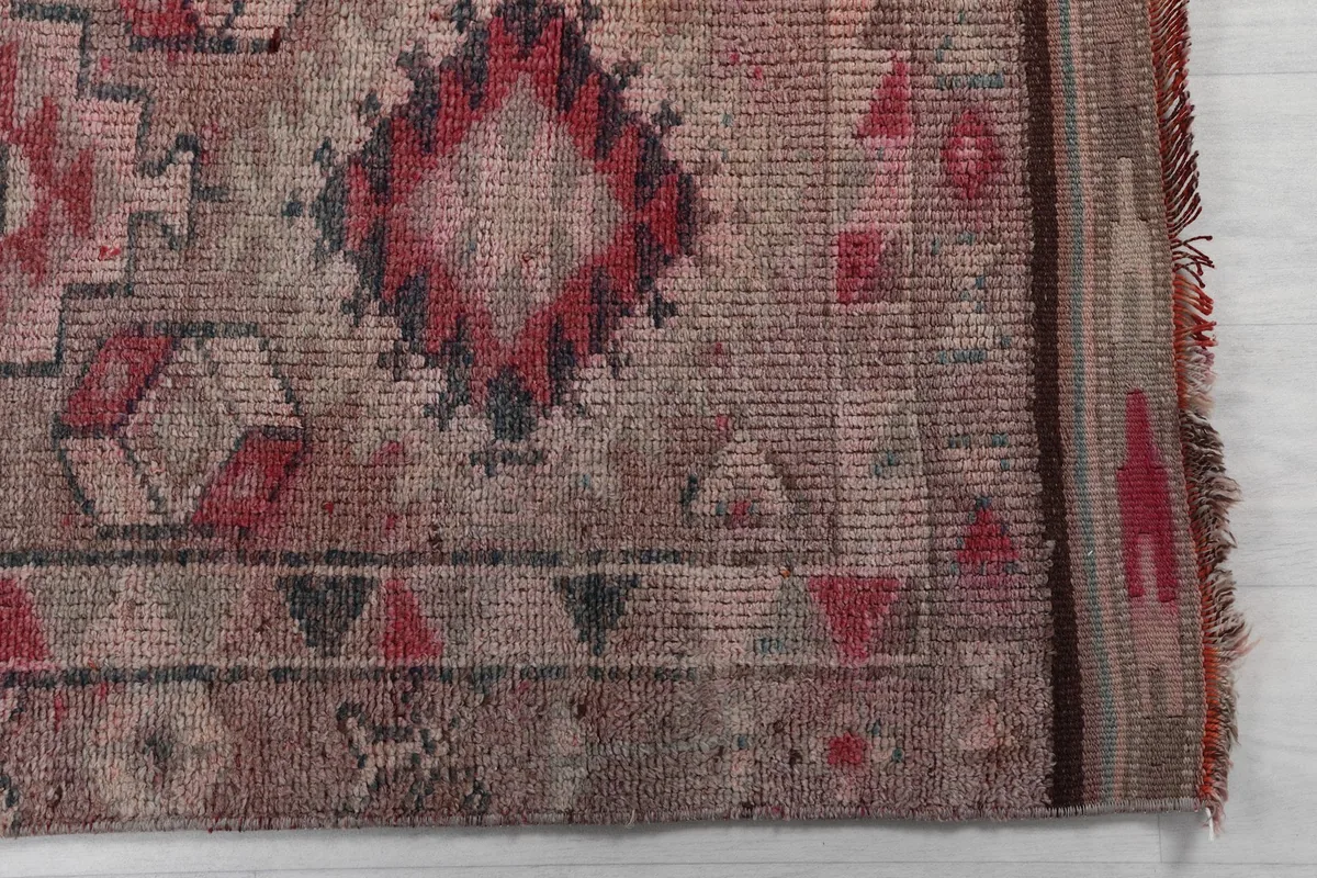 Detailed view of the rug's border and a prominent red geometric motif with faded colors