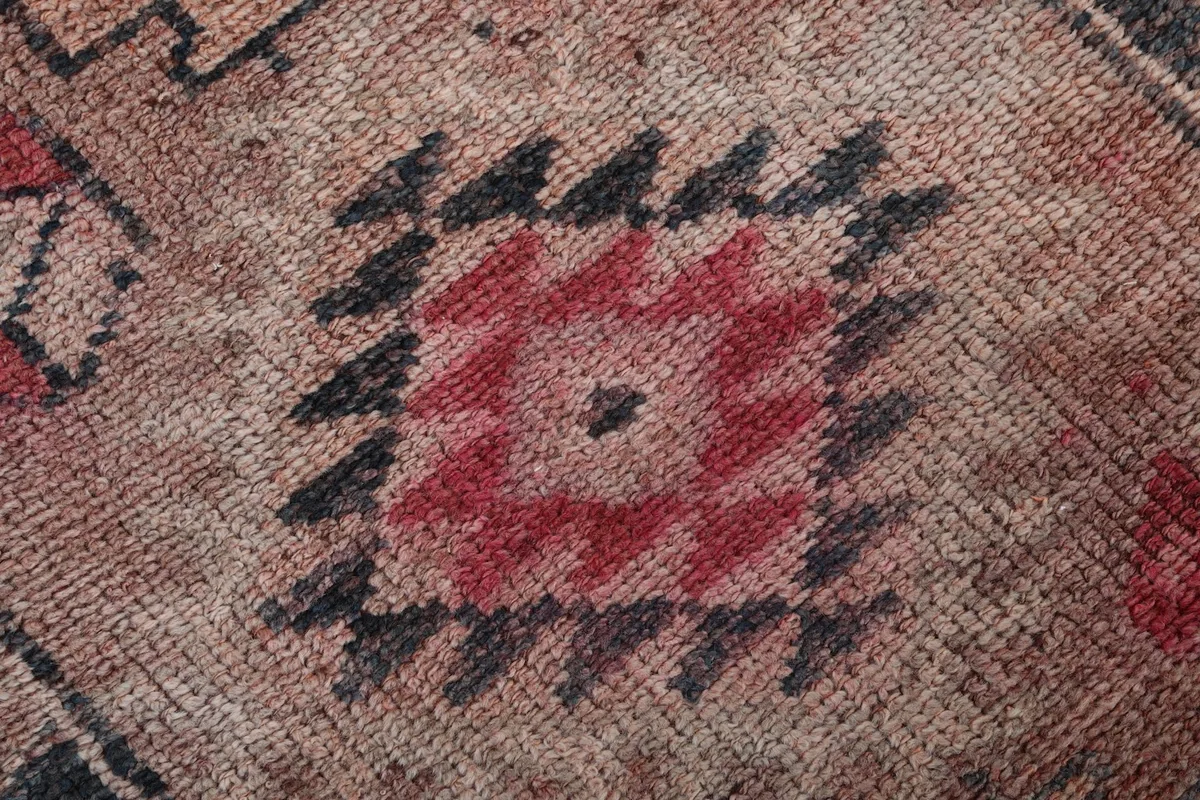 Macro shot of a red and black geometric pattern, highlighting the hand-knotted wool pile and wear