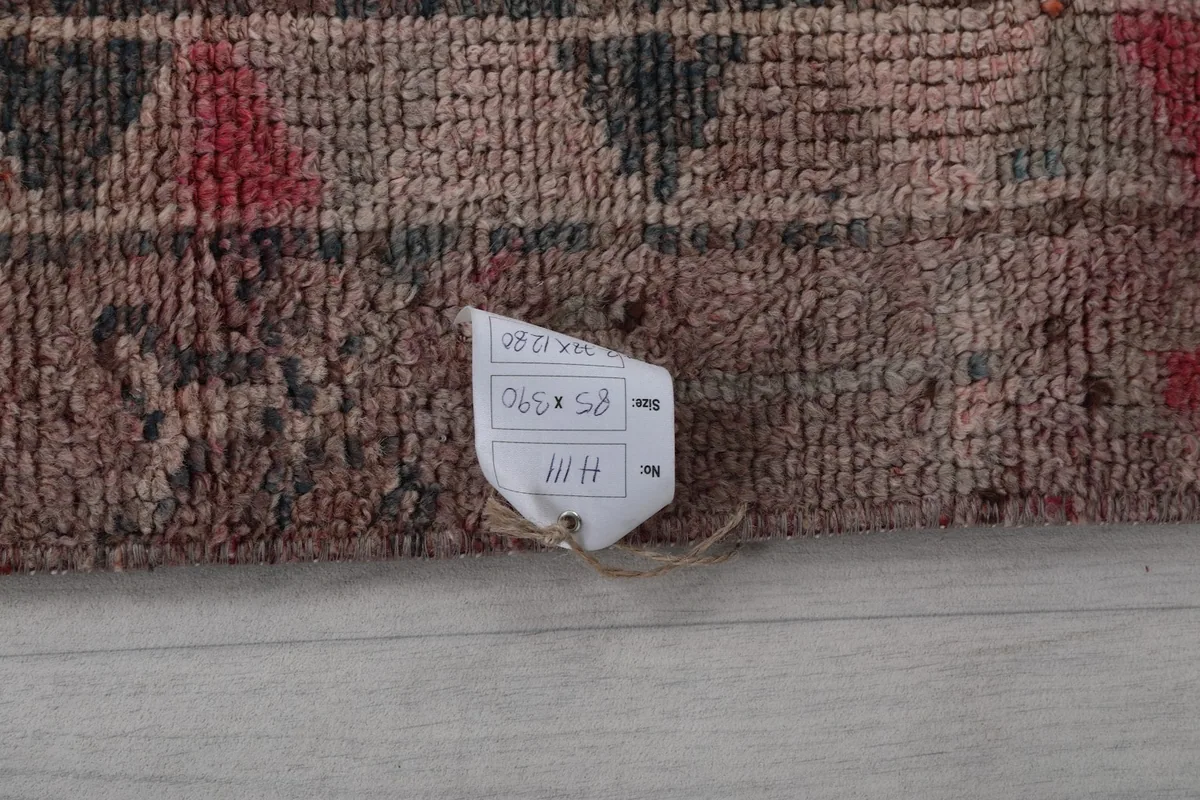 White tag attached to the rug's back, displaying its dimensions and origin details