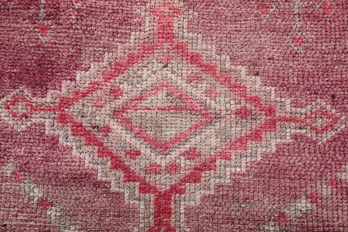 Macro shot of a central geometric motif in rose and gray, showcasing the knotting