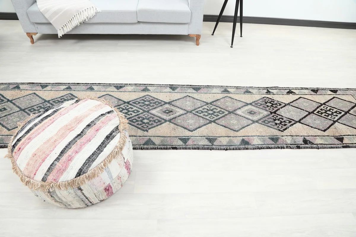 Long view of the runner rug on a light floor, with an ottoman in the foreground