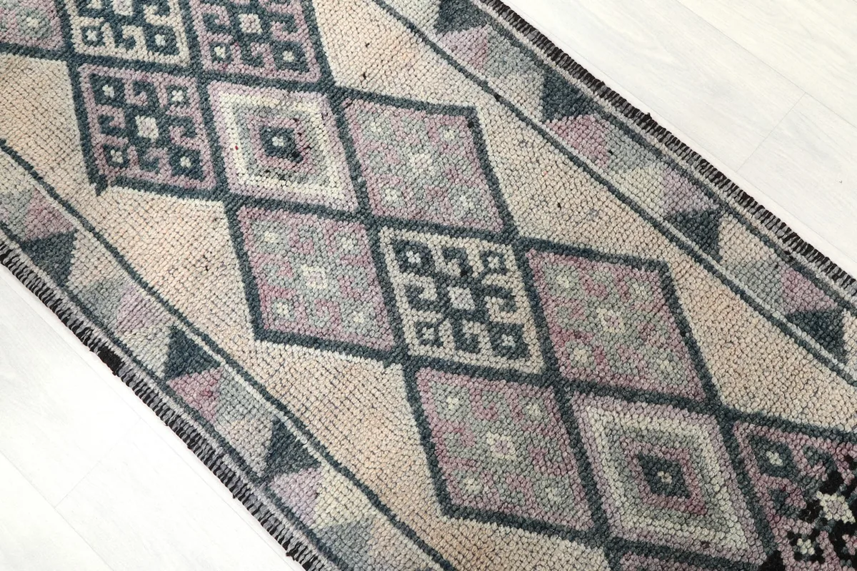 Overhead close-up showing the varied gray, rose, and black geometric patterns on the beige field