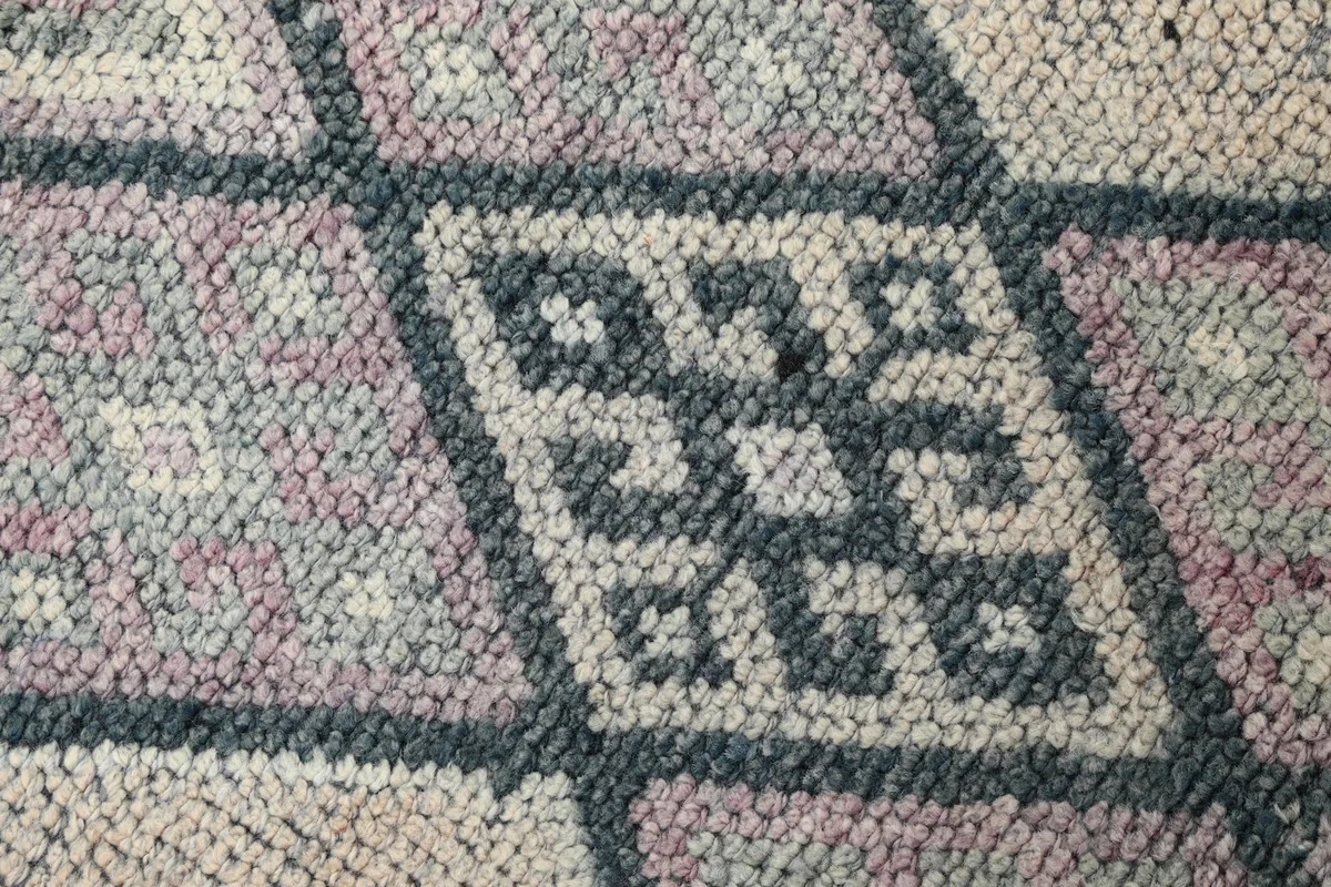Macro shot of the rug's low wool pile, revealing the hand-knotted texture and color variations