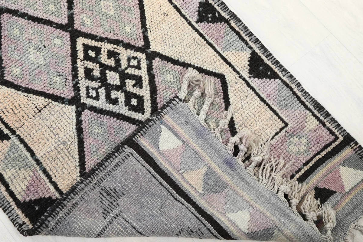 Folded corner of the rug, revealing the cotton foundation and the reverse side of the knotting