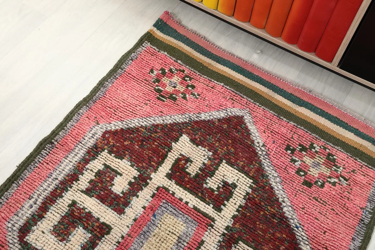 Overhead angled shot of the runner's end, showing the pink field, geometric pattern, and colorful border stripes.
