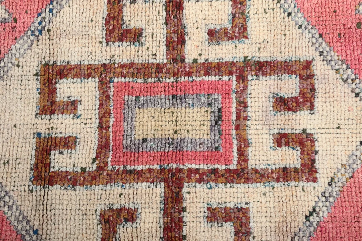 Close-up of a central geometric motif in ivory and brown, highlighting the hand-knotted wool texture.