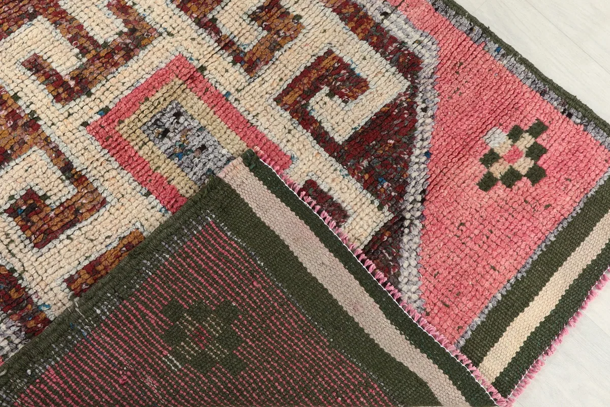 Partial view of the rug's reverse side, showing the hand-knotted cotton foundation and wool pile.