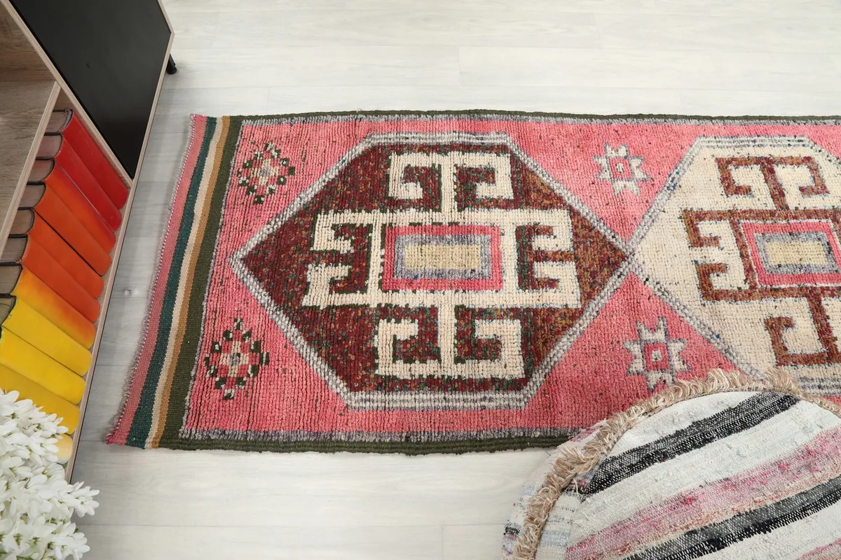 Overhead view showing a section of the runner rug with its pink field and detailed brown and ivory patterns.