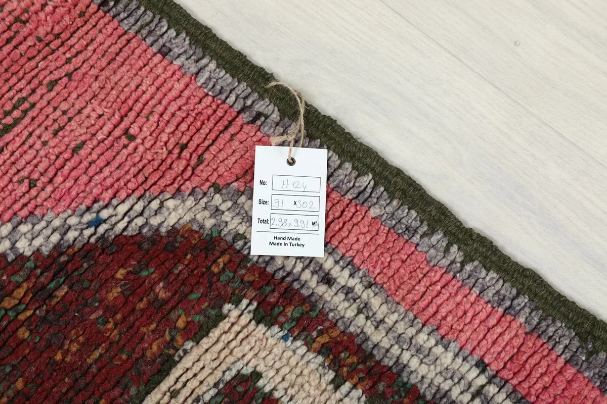 Corner of the rug with a product tag, displaying details about its origin and hand-knotted craftsmanship.