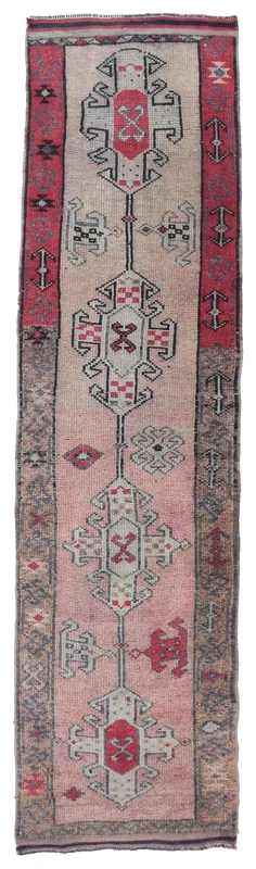 Full overhead view of the vintage Anatolian runner rug with rose, red, and gray geometric patterns.