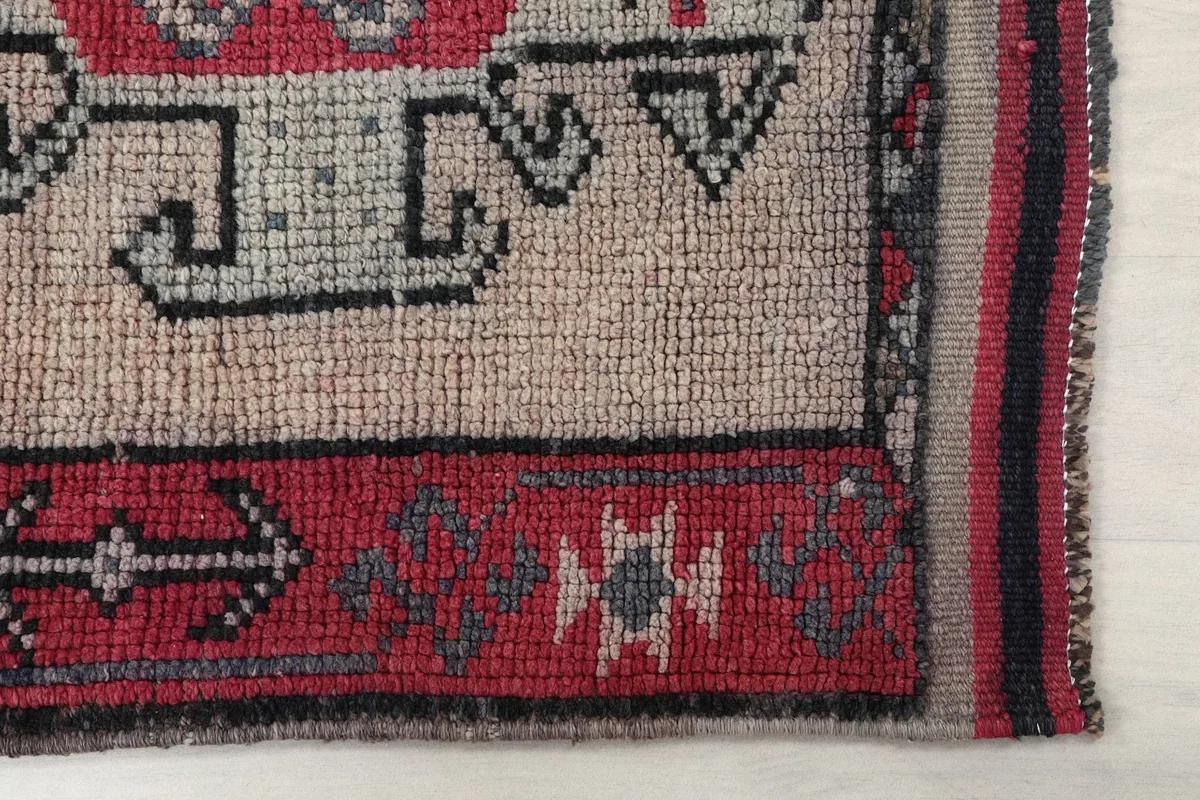 Detail of the rug's corner, showing the red border and a small section of the main rose field.