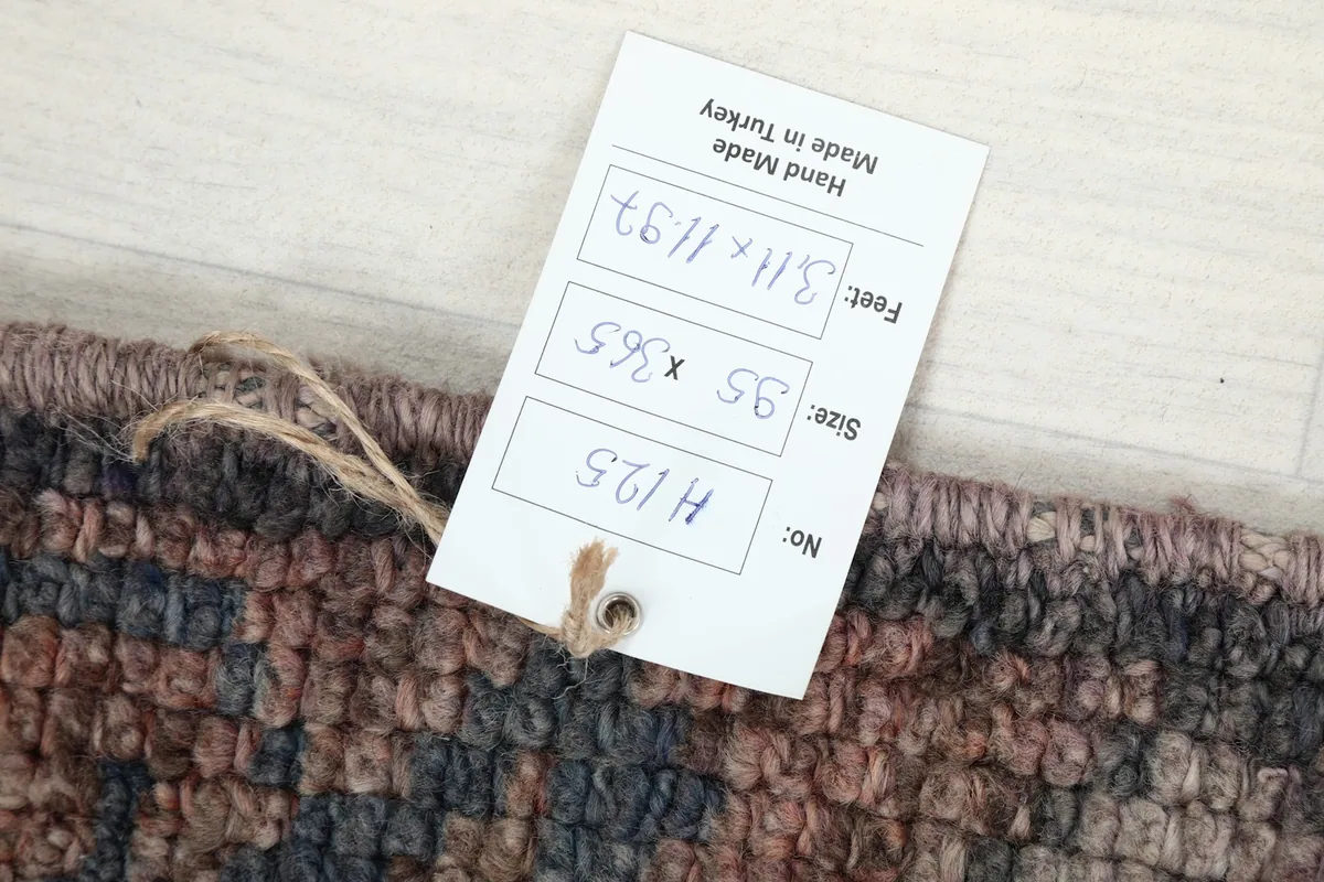 Product tag attached to the rug, displaying its size in feet and centimeters and 'Hand Made in Turkey'.