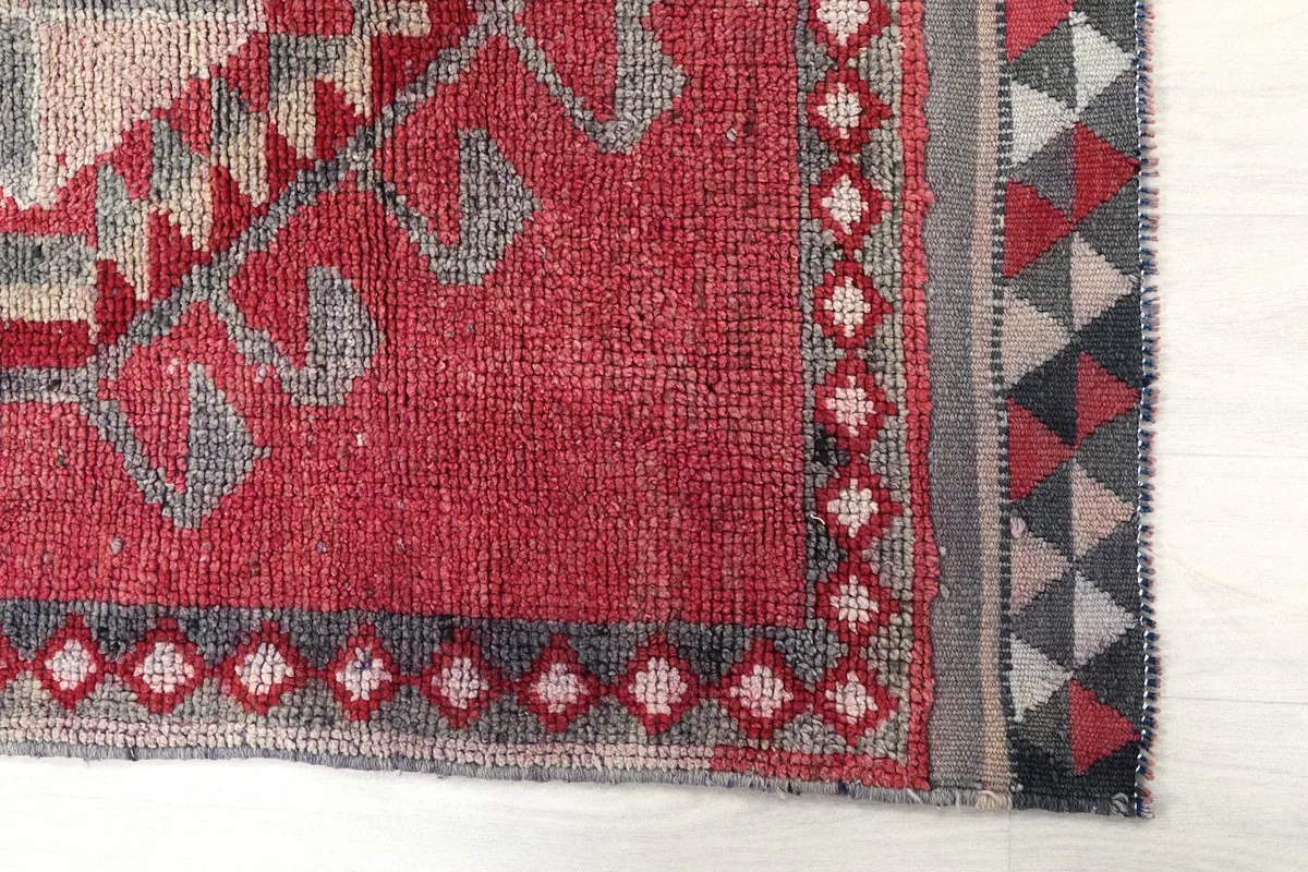 Detailed view of the rug's side border with small geometric patterns and the main rose field.