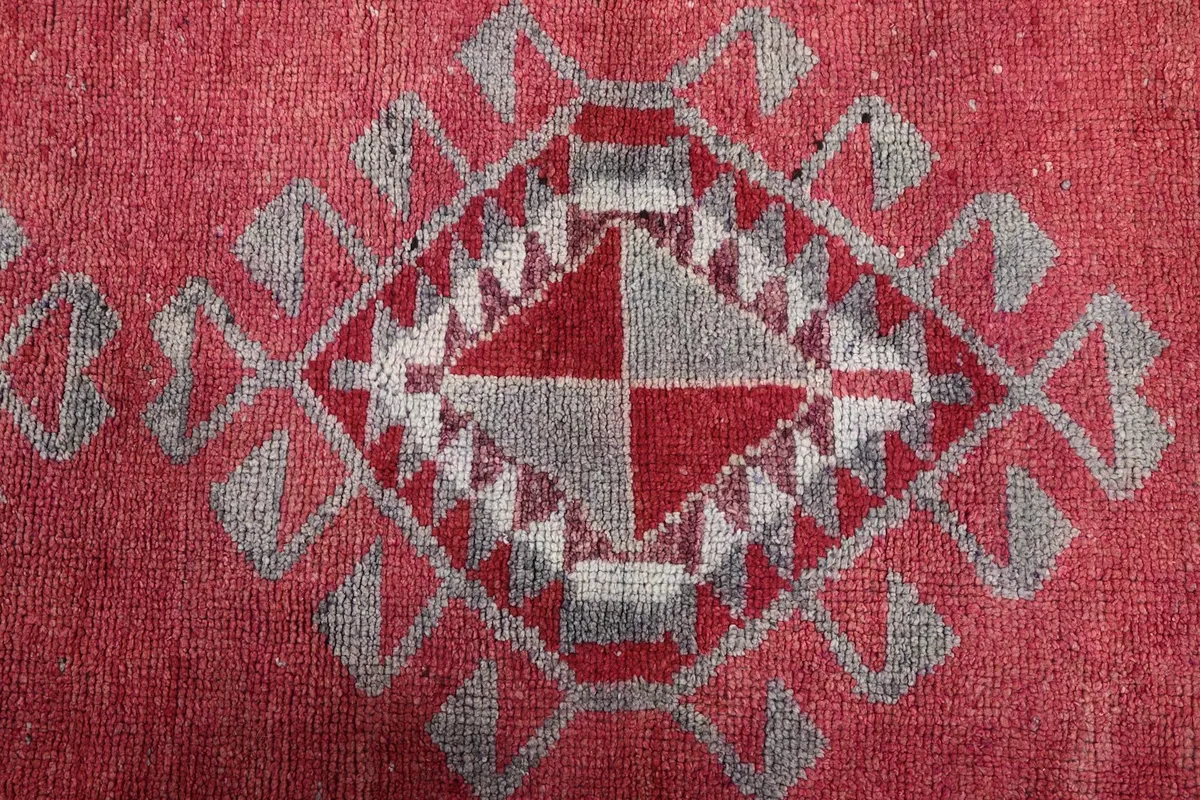 Overhead close-up of a prominent gray and red geometric medallion within the runner's design.