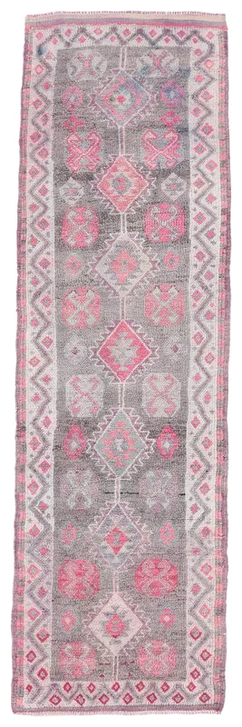Full overhead view of the gray and pink vintage runner rug on a white background
