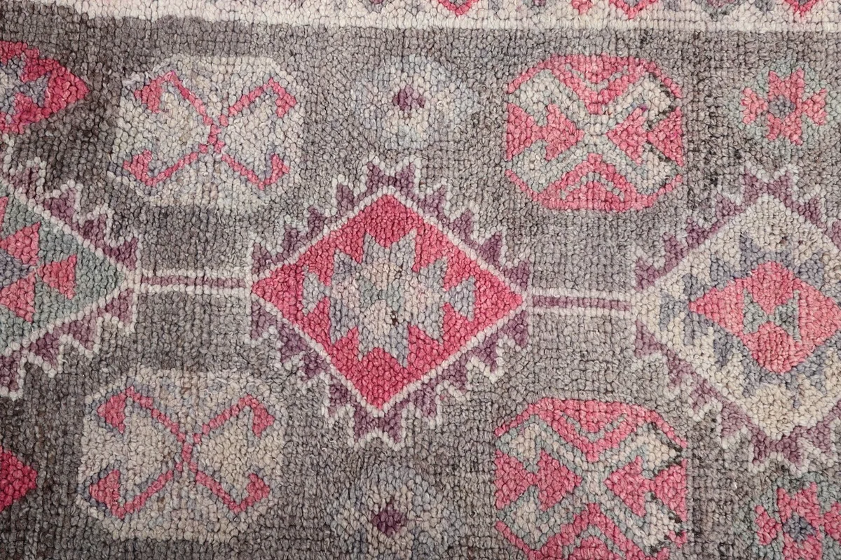 Close-up of the central geometric patterns, including diamond and square shapes in pink and gray