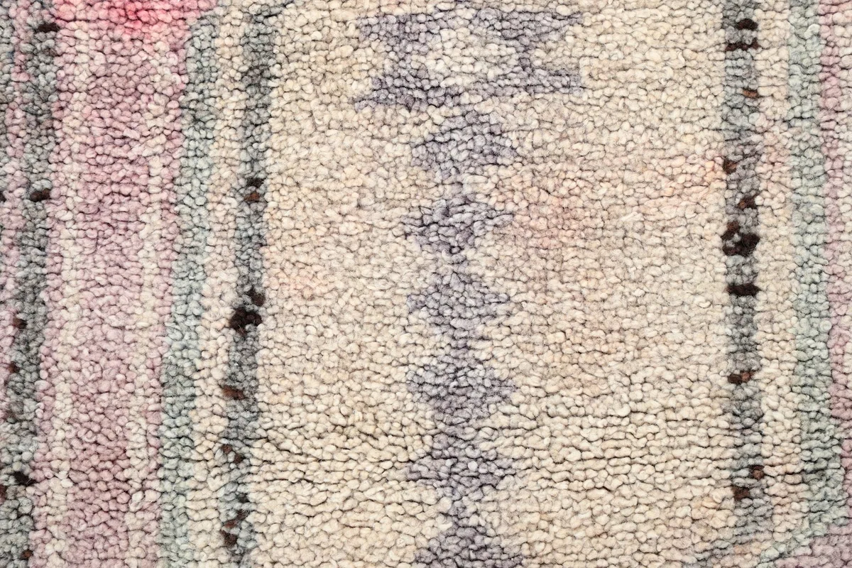 Texture of the hand-knotted wool pile, showing variations in color and wear.