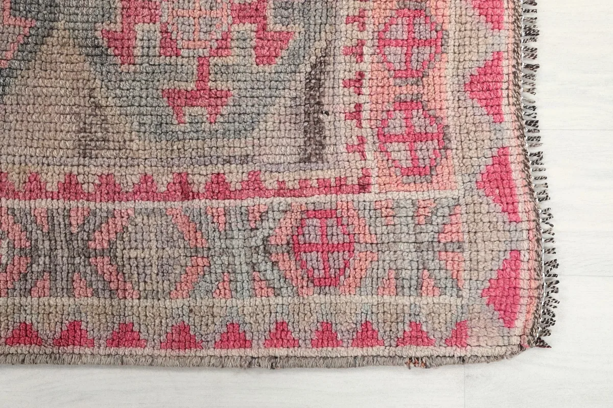 Detailed view of the rug's border and field design, showing rose and gray tones