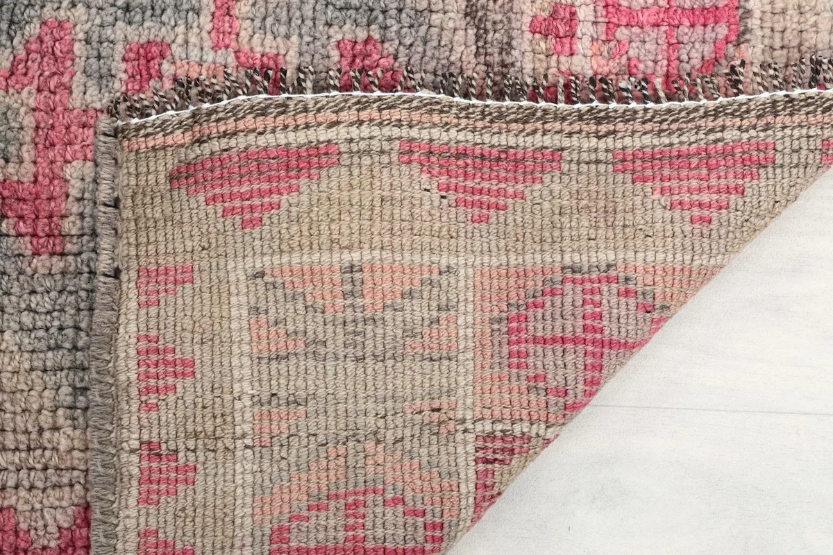 Close-up of the rug's low pile and knotting structure, showing the aged texture